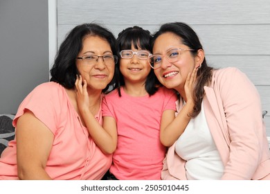 Three Generations of women Grandmother, mom and brunette Latina daughter with glasses show their love and celebrate Mother's Day - Powered by Shutterstock