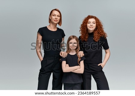 three generations of women in matching clothes standing on grey background, stylish family