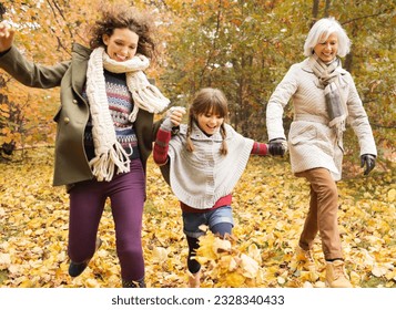 Three generations of women playing in autumn leaves - Powered by Shutterstock