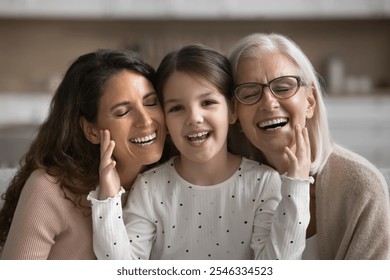 Three generations of women portrait. Preschooler girl, mother and grandmother sit on sofa, enjoy moments of warmth and harmony. Multigenerational family ties, connection between diverse generations - Powered by Shutterstock