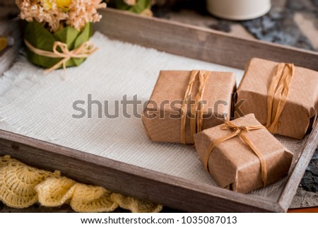 Three gift boxes in a kraft wrapper on a gray concrete background on a wooden table. place for your inscription