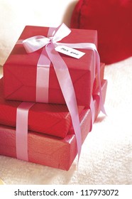 three gift boxes wrapped in red with a ribbon around the whole package