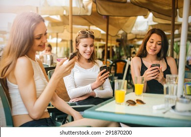 Three girl at the cafe sending text messages