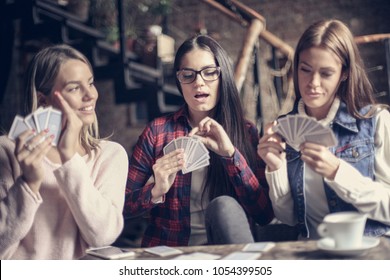 Three Girls In Cafe Playing Game Cards.