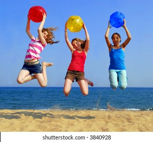 Three Girls With Colorful Beach Balls Jumping On A Seashore