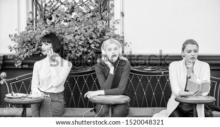 three girls do different things. different ways to relax. girls in cafe. social diversity. listening music. reading book. speaking on phone. frienship. free time spending. relax. business meeting.
