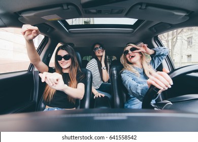 three girls driving in a convertible car and having fun