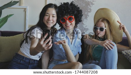 Three girls friends make selfie. Young women grimasing and posing funny at home