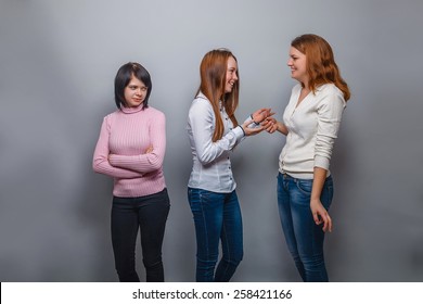 Three girls girlfriends talking two, one was offended on a gray background - Shutterstock ID 258421166