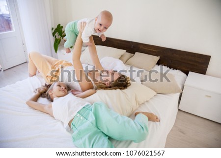 three girls play sisters in the morning in the bedroom on the bed