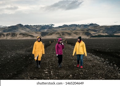 Three girls in raincoats at Iceland road. Iceland landscape