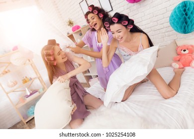 Three Girls In Robes With Curlers In Their Hair Pillow Fight. They Are Celebrating Women's Day March 8.