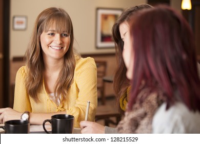 Three girls sit at a table with coffee and study.