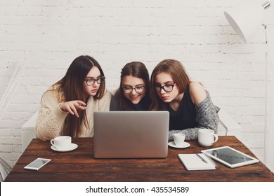 Three girls work and coffee with laptop. Young girls friends happy with computer. Discussion, startup, friendly conversation. Women friendship, modern life, gossip and internet dating concept. - Powered by Shutterstock