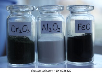 Three Glass Jars With Metal Oxides: Chromium Oxide, Aluminum Oxide And Iron Oxide.