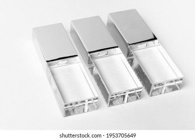 Tres unidades USB transparentes de vidrio con una cubierta metálica sobre un fondo gris. Diseño. Foto de primer plano. Copiar espacio. Una alta resolución.