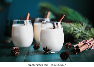 Three glasses of creamy eggnog with cinnamon sticks and star of anise. Selective focus with blurred festive background. - Powered by Shutterstock