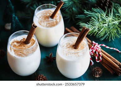 Three glasses of creamy eggnog with cinnamon sticks and star of anise. Selective focus with blurred festive background. - Powered by Shutterstock