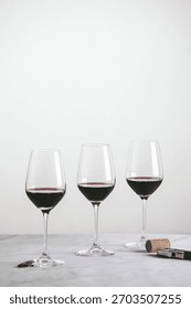 Three Glasses of Red Wine Setup on Marble White Background with Corkscrew Wine Opener Ready to be Served on the Tasting Table  