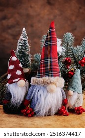 three gnomes with long white beards, in caps and coats, gathered near fir branches decorated with toys to celebrate Christmas, a warm New Year's atmosphere, a holiday card, a good story
