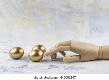 Three golden eggs touched by wooden puppet finger against painted sky background - Powered by Shutterstock