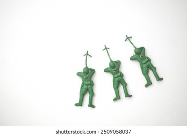 Three green plastic toy soldiers arranged in a playful line on a white background. - Powered by Shutterstock