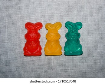 Three Gummy Easter Bunnies Candy On Solid Light Background Overhead