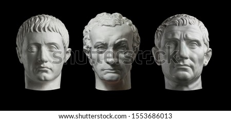 Three gypsum copy of ancient statue heads isolated on a black background. Plaster sculpture mans faces.