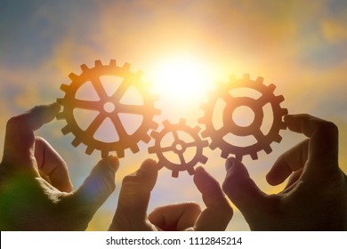 three hands of businessmen collect the gear from the gears of the details of the puzzles. against the background of sunlight. Concept business idea. Teamwork, cooperation, strategy - Shutterstock ID 1112845214