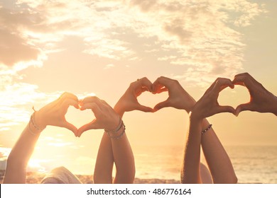 three hands of a heart-shaped woman hurled into the sky at sunset