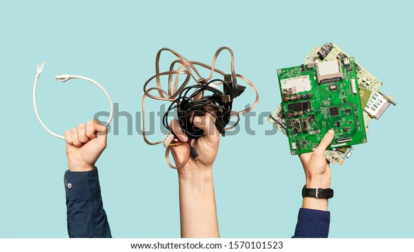 Three hands hold electrical waste on blank\
blue background.