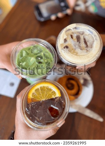 Three hands holding glasses of sweet drinks on a wooden table background. Celebrating with friends at the bar.