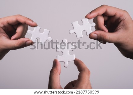 three hands trying to connect couple puzzle piece with gray background. Jigsaw puzzle team work concept. one part of whole. symbol of association and connection. business strategy.