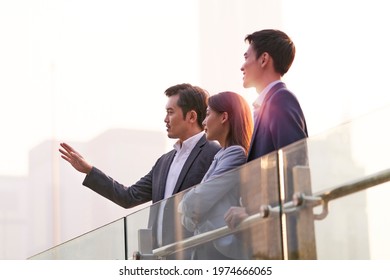 three happy asian businesspeople chatting talking discussing business outdoors - Powered by Shutterstock