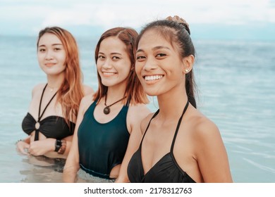 Three Happy Asian Women Smiling While Taking A Dip At The Beach And Having Fun. 3 Friends Bonding Together And Looking At Camera.