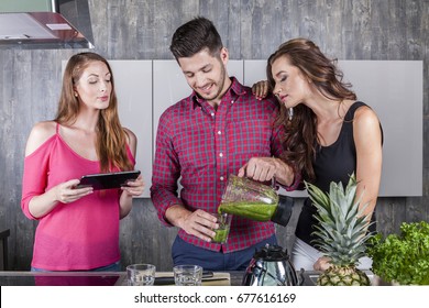 three happy attractive friends in the kitchen preparing a green tasty healthy smoothie drink made of green vegetables fruits and herbs - Powered by Shutterstock