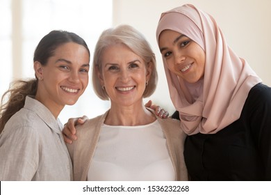 Three Happy Beautiful Diverse Two Generation Women Young Asian Muslim Woman Wear Hijab And Caucasian Older Mature Female Multicultural Ladies Bonding Standing Together Looking At Camera, Portrait