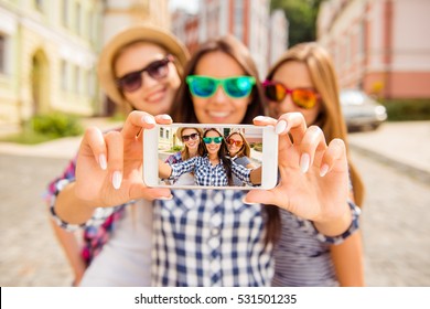 Three happy best girlfriends in glasses making selfie on smartphone. - Powered by Shutterstock