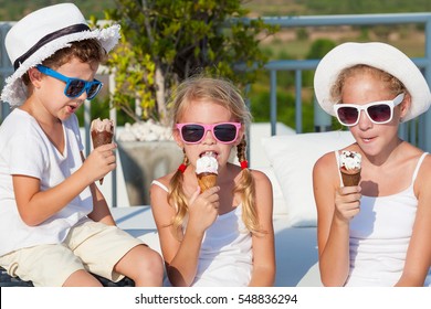 Three Happy Children Eating Ice Cream Near Swimming Pool At The Day Time. Concept Healthy Food. People Having Fun Outdoors. Concept Of Friendly Family, Summer Vacation And Healthy Food.