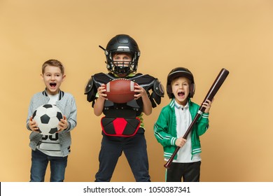 Three Happy Children Show Different Sport. Studio Fashion Concept. Emotions Concept. Boys Likes Sport. Football, American Football And Baseball. Children's Fashion Show. Sport Style. Teen And Kids