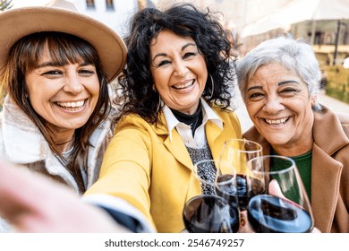 Three happy elderly women toasting and drinking red wine outside at bar restaurant - Group of retired female friends taking selfie picture outdoor - Family generation, mature female life style concept - Powered by Shutterstock