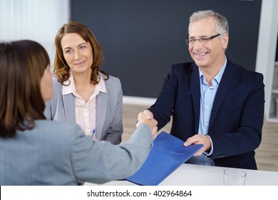 Three Happy Executives Closing An Important Business Transaction Or Negotiation And Exchanging Documents While Sitting In Office With Copy Space