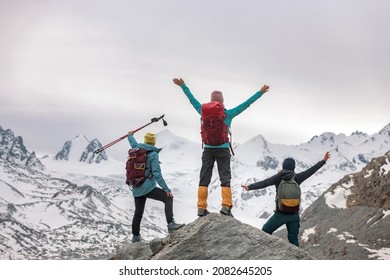 Three happy female hikers are standing with open arms in mountains and looks at glacier - Powered by Shutterstock