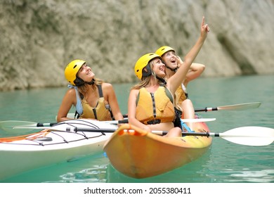 Three happy friends in kayak enjoying views pointing above in a lake