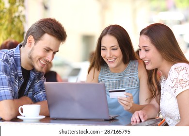 Three Happy Friends Shopping Online With A Credit Card And A Laptop In A Coffee Shop