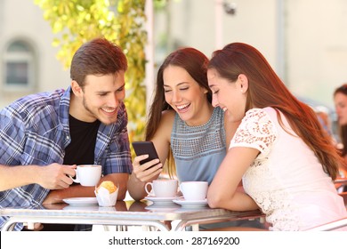 Three Happy Friends Watching Social Media In A Smart Phone In A Coffee Shop