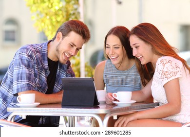 Three happy friends watching tv or social media in a tablet in a coffee shop terrace - Powered by Shutterstock