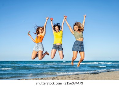 three happy girls on jumping motion at the sand beach outdoors in summer celebrating hot vacation days. happy funny friends having fun on warm seaside holidays joy, carefree, genz and party concept - Shutterstock ID 2156374473