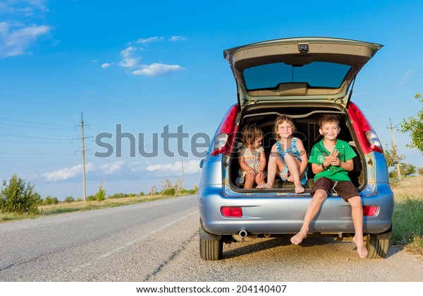 three happy kids in car, family trip, summer\
vacation travel