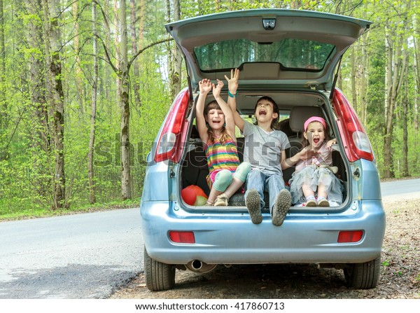 three happy kids in car, family trip, summer\
vacation travel